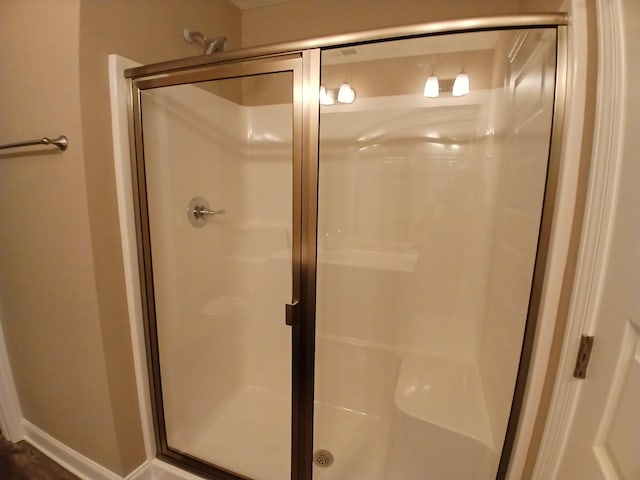 full bathroom with a stall shower and baseboards