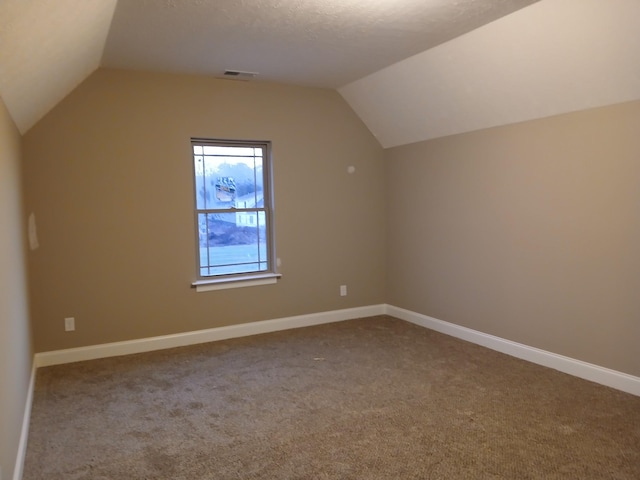 additional living space featuring carpet, lofted ceiling, visible vents, a textured ceiling, and baseboards