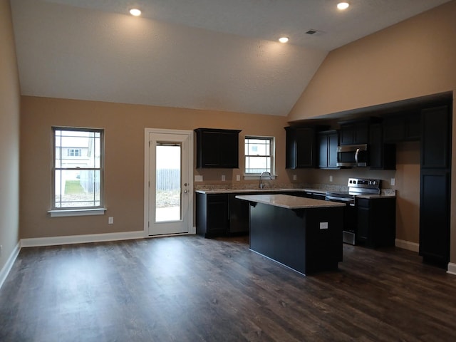 kitchen with stainless steel appliances, a kitchen island, baseboards, vaulted ceiling, and dark wood finished floors