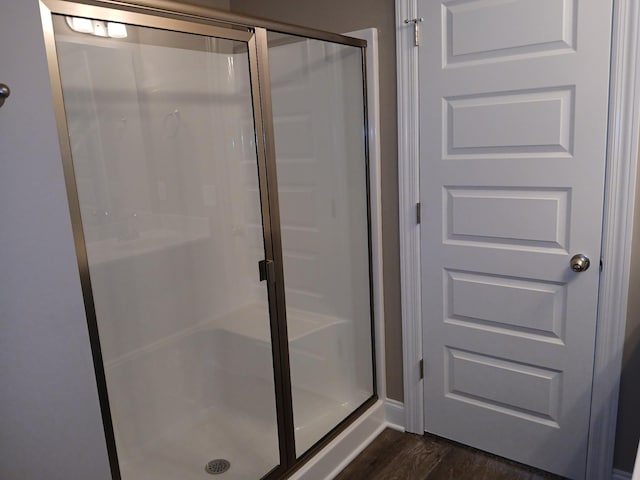 full bathroom featuring a shower stall and wood finished floors