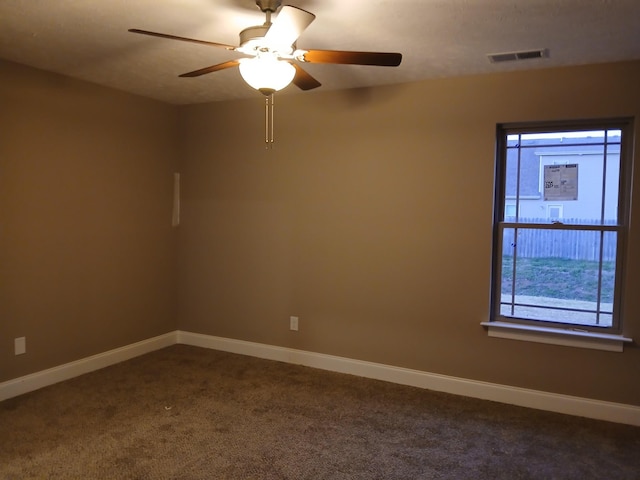 empty room with dark colored carpet, visible vents, and baseboards