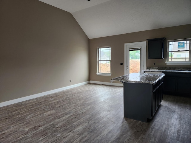 kitchen with dark wood-type flooring, open floor plan, vaulted ceiling, a kitchen island, and baseboards