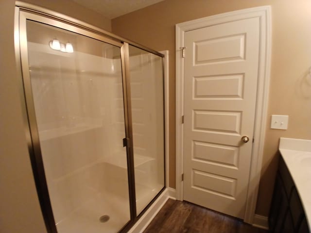 bathroom with wood finished floors, a shower stall, and vanity