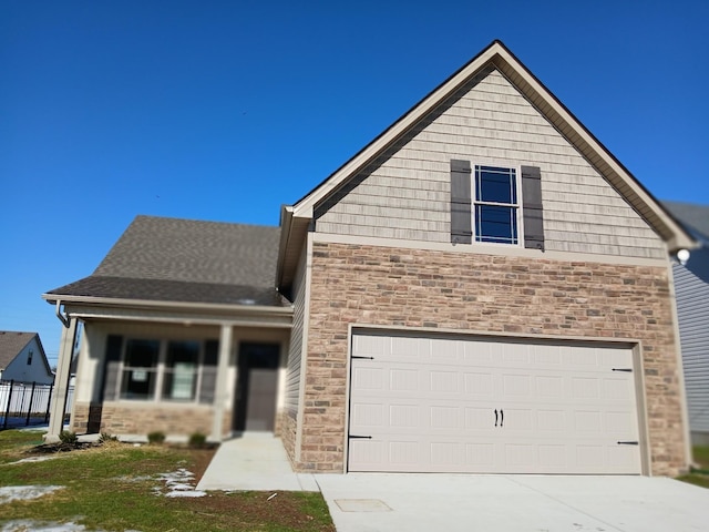 view of front of house with stone siding, a shingled roof, and concrete driveway