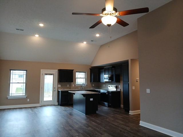 kitchen with light countertops, appliances with stainless steel finishes, dark wood-type flooring, a kitchen island, and dark cabinetry