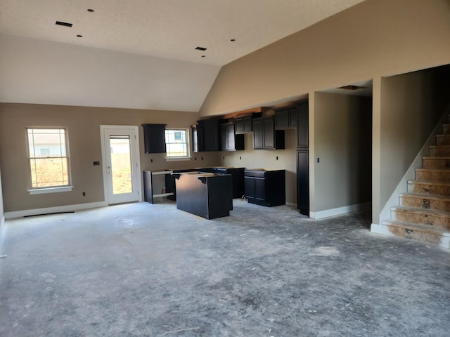 kitchen with lofted ceiling, open floor plan, a kitchen island, and baseboards