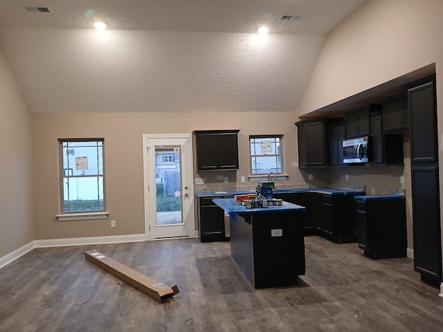 kitchen featuring lofted ceiling, stainless steel microwave, dishwasher, and a center island