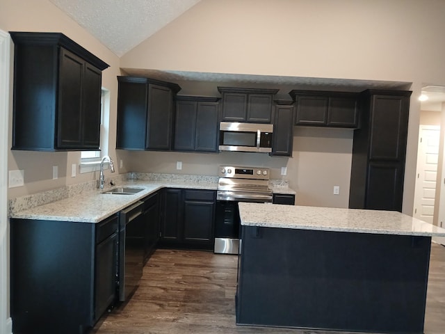 kitchen with appliances with stainless steel finishes, a sink, a center island, and dark cabinets