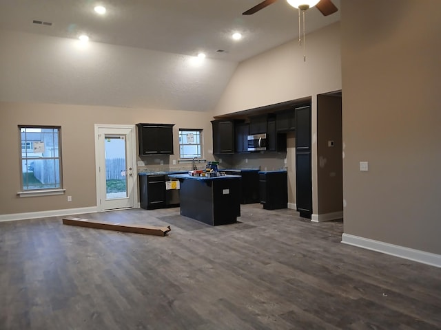 kitchen with a kitchen island, stainless steel microwave, open floor plan, and dark cabinets