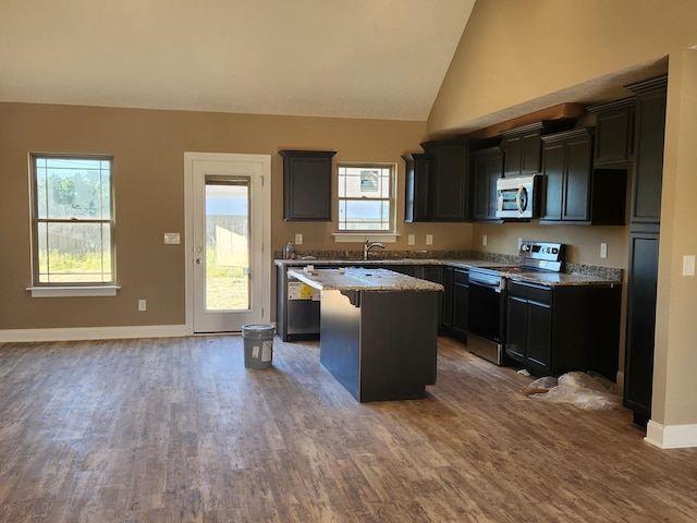 kitchen featuring stainless steel appliances, a center island, dark wood-style floors, and light stone countertops