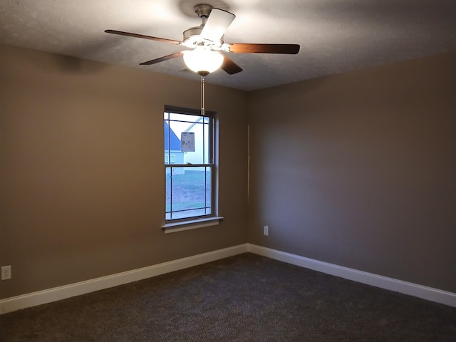 spare room featuring dark carpet, baseboards, and ceiling fan