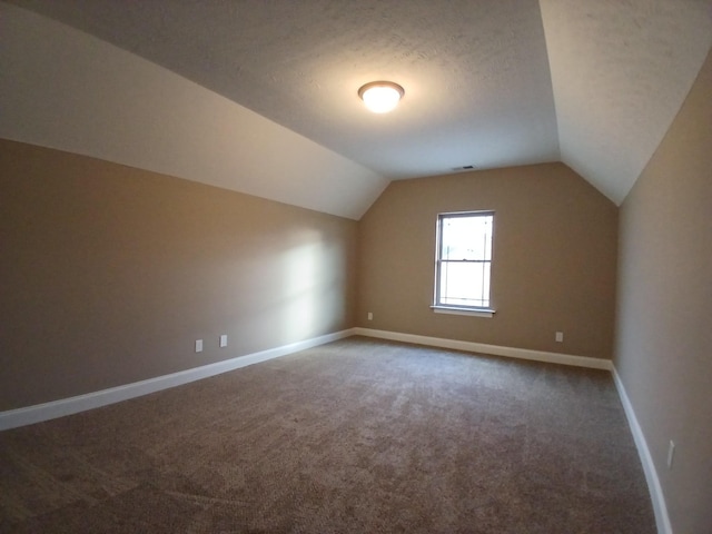 additional living space featuring carpet, vaulted ceiling, a textured ceiling, and baseboards