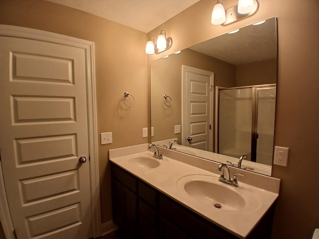 bathroom with double vanity, a sink, and a shower with door