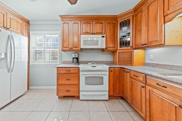 kitchen with white appliances, light tile patterned floors, light stone counters, and brown cabinets