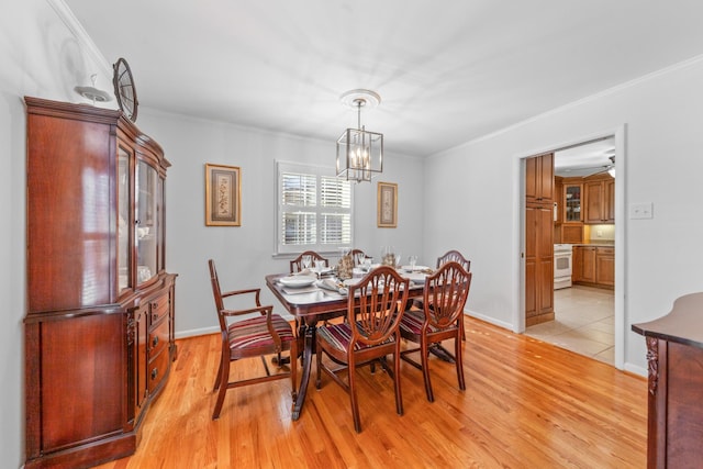 dining area with light wood-style floors, baseboards, ornamental molding, and a chandelier