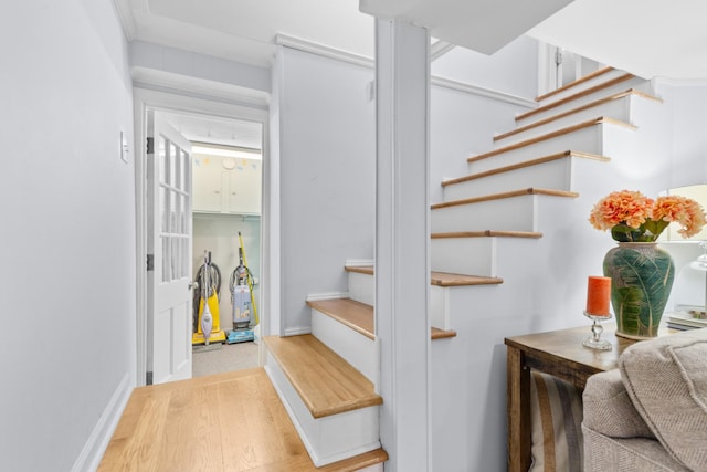 staircase featuring wood finished floors and baseboards