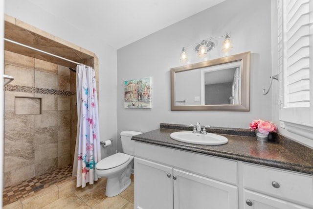 bathroom with toilet, a tile shower, and vanity