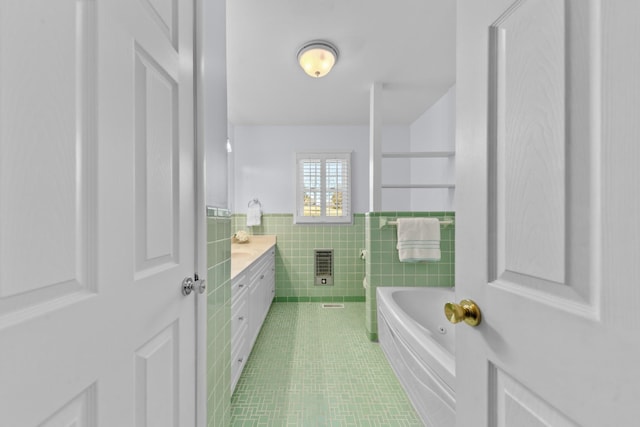 full bathroom with tile patterned flooring, tile walls, vanity, a bath, and heating unit