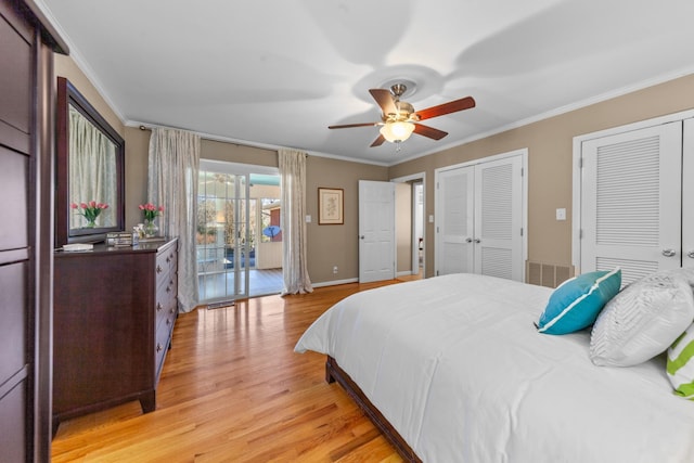 bedroom with crown molding, light wood finished floors, two closets, visible vents, and baseboards