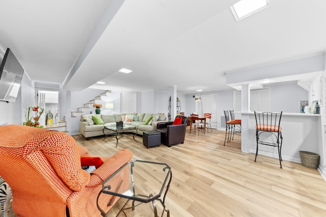 living room with light wood-style flooring, stairs, and baseboards