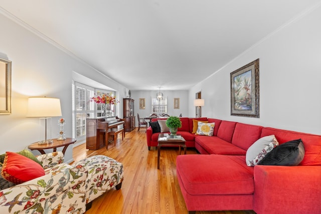 living room featuring light wood-style floors, crown molding, and a notable chandelier