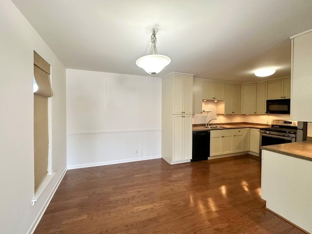 kitchen featuring baseboards, dark wood-style flooring, hanging light fixtures, black appliances, and a sink