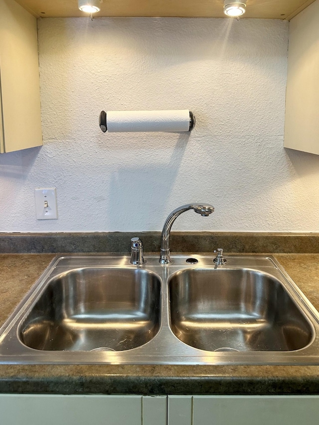 details featuring dark countertops, a sink, and a textured wall