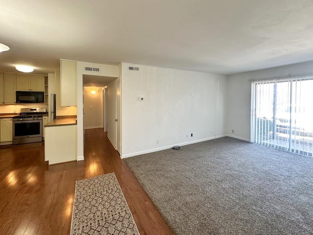 unfurnished living room with dark wood-type flooring, visible vents, and baseboards