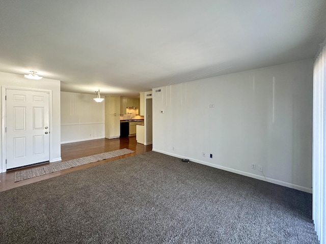 unfurnished living room featuring dark colored carpet and baseboards