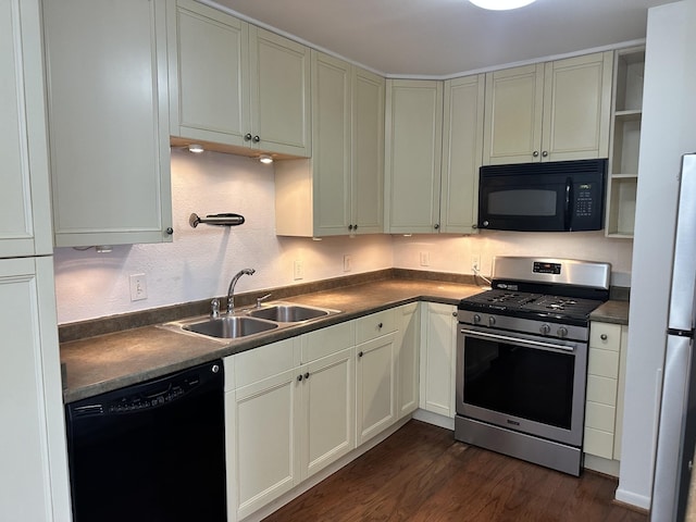 kitchen featuring dark countertops, black appliances, dark wood finished floors, and a sink