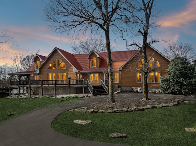 view of front of property featuring driveway, metal roof, and a lawn