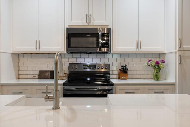 kitchen with stainless steel appliances, light stone counters, and white cabinets