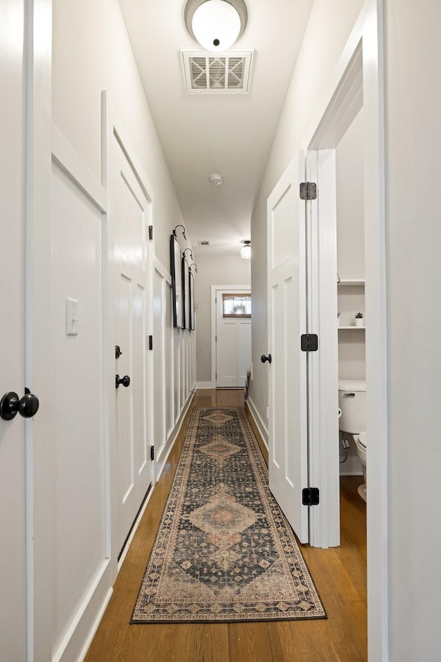 hallway featuring wood finished floors and visible vents