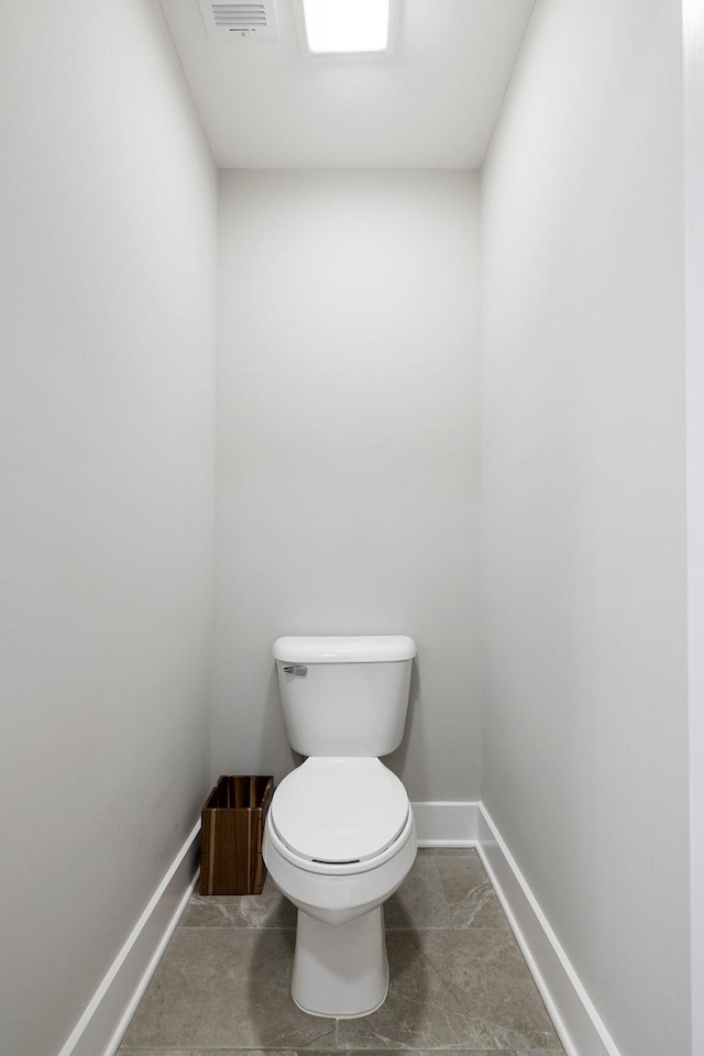 bathroom featuring toilet, visible vents, and baseboards