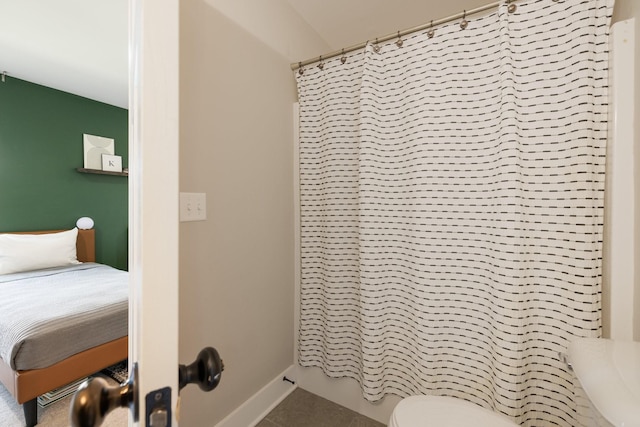 bathroom featuring toilet, a shower with curtain, and baseboards