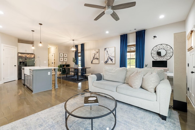 living area featuring ceiling fan with notable chandelier, light wood finished floors, visible vents, and recessed lighting