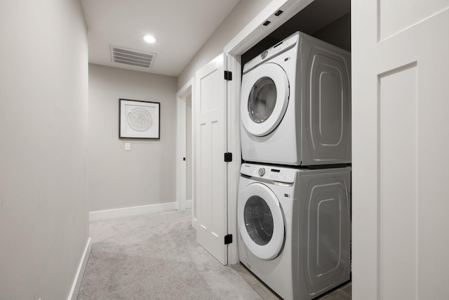 laundry area with light colored carpet, laundry area, stacked washer / dryer, visible vents, and baseboards