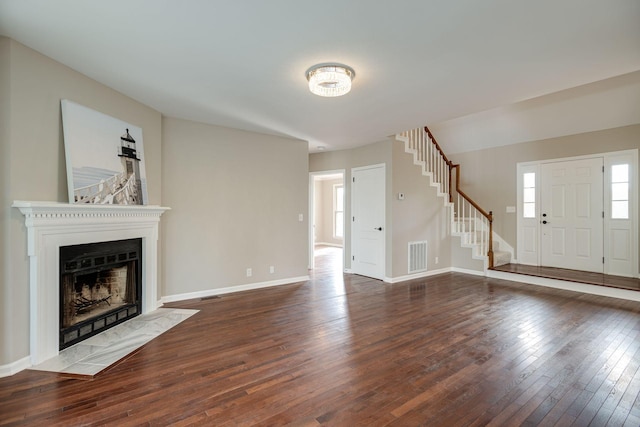 unfurnished living room featuring a fireplace, visible vents, baseboards, stairway, and dark wood-style floors