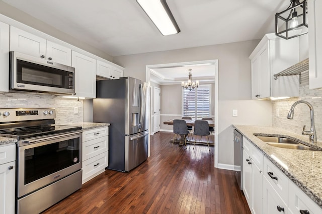 kitchen with white cabinets, stainless steel appliances, a sink, and hanging light fixtures