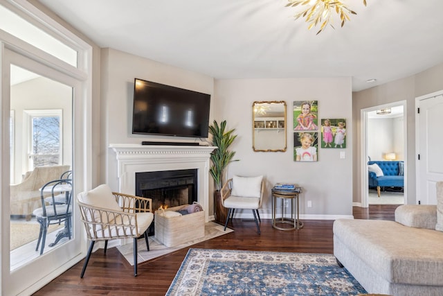 living area featuring dark wood-style floors, a fireplace with flush hearth, and baseboards