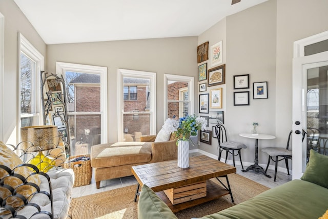 living area featuring lofted ceiling, light tile patterned floors, and baseboards