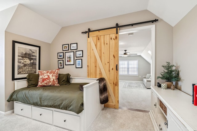 bedroom featuring lofted ceiling, a barn door, and light colored carpet