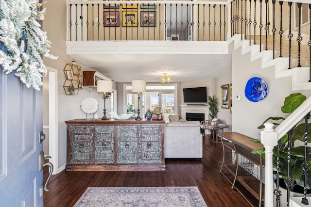 living area featuring a fireplace, dark wood finished floors, and stairs