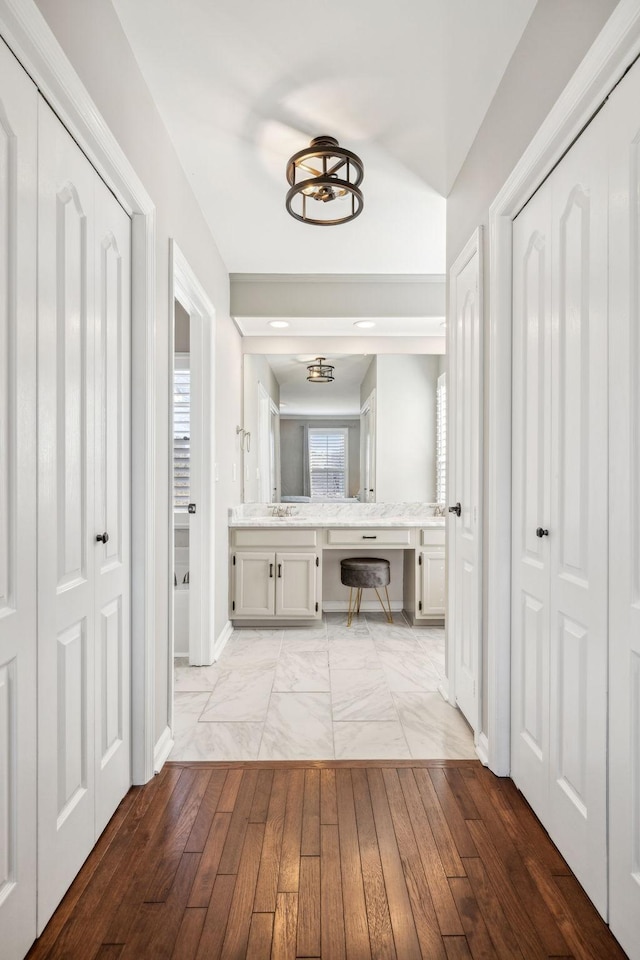 hallway with light wood-type flooring, baseboards, and a sink