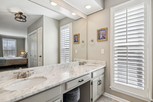 ensuite bathroom with double vanity, marble finish floor, connected bathroom, and a sink