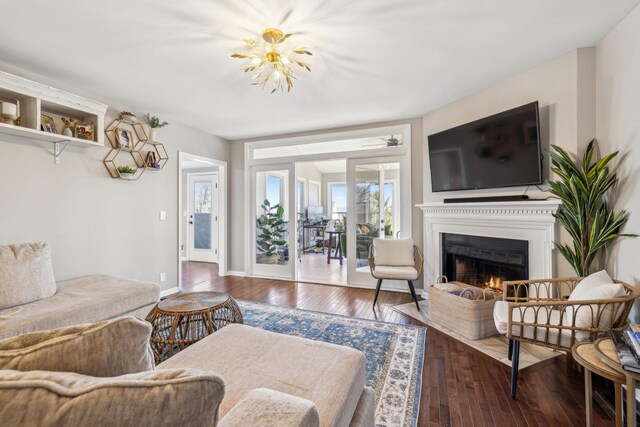 living area with a lit fireplace, dark wood-style flooring, and baseboards