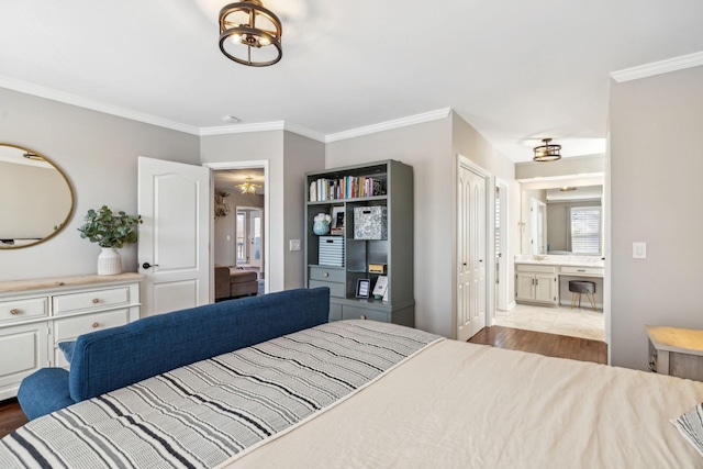 bedroom featuring light wood-style floors, connected bathroom, and crown molding