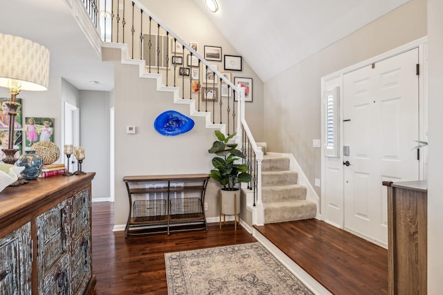 entryway with high vaulted ceiling, stairs, baseboards, and dark wood-type flooring