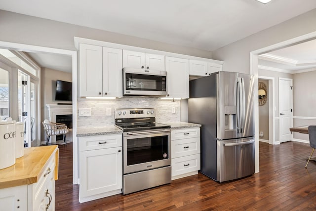 kitchen with wooden counters, appliances with stainless steel finishes, white cabinetry, and tasteful backsplash