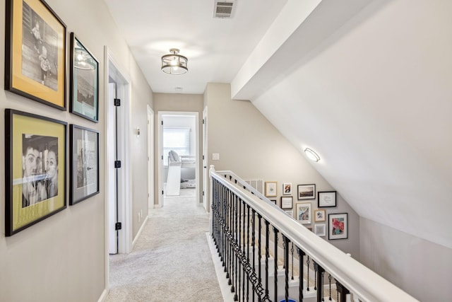 corridor featuring visible vents, vaulted ceiling, light carpet, and an upstairs landing